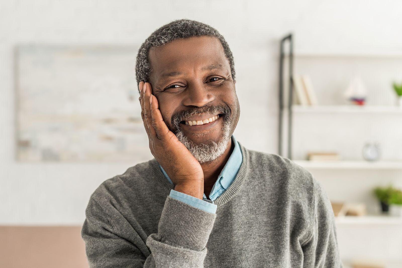 happy african american man holding hand near face while smiling at camera